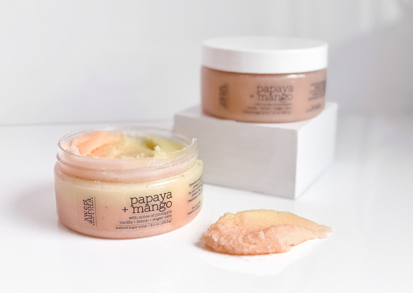 Papaya + Mango sugar scrub showing exfoliating texture and product jars