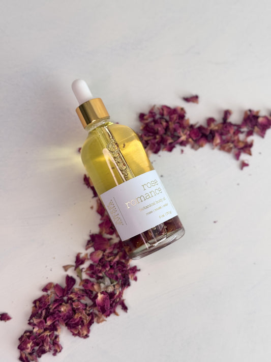 Rose Romance Body Oil with dried rose petals on a light background by Sweet Aurora