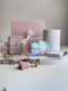 Candle,meditation cards and wick trimmer items on a white surface with a pink box in the background.