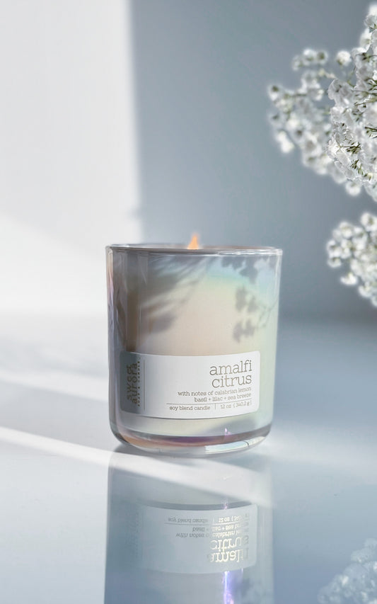 Lit Amalfi Citrus soy wooden wick candle in a bright, sunlit setting