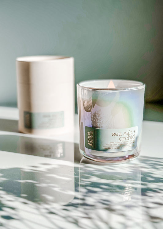 Lit Sea Salt + Orchid soy wooden wick candle in an iridescent glass vessel